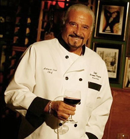 Chef Arturo Cea with his white uniform and a cup of wine in the right hand